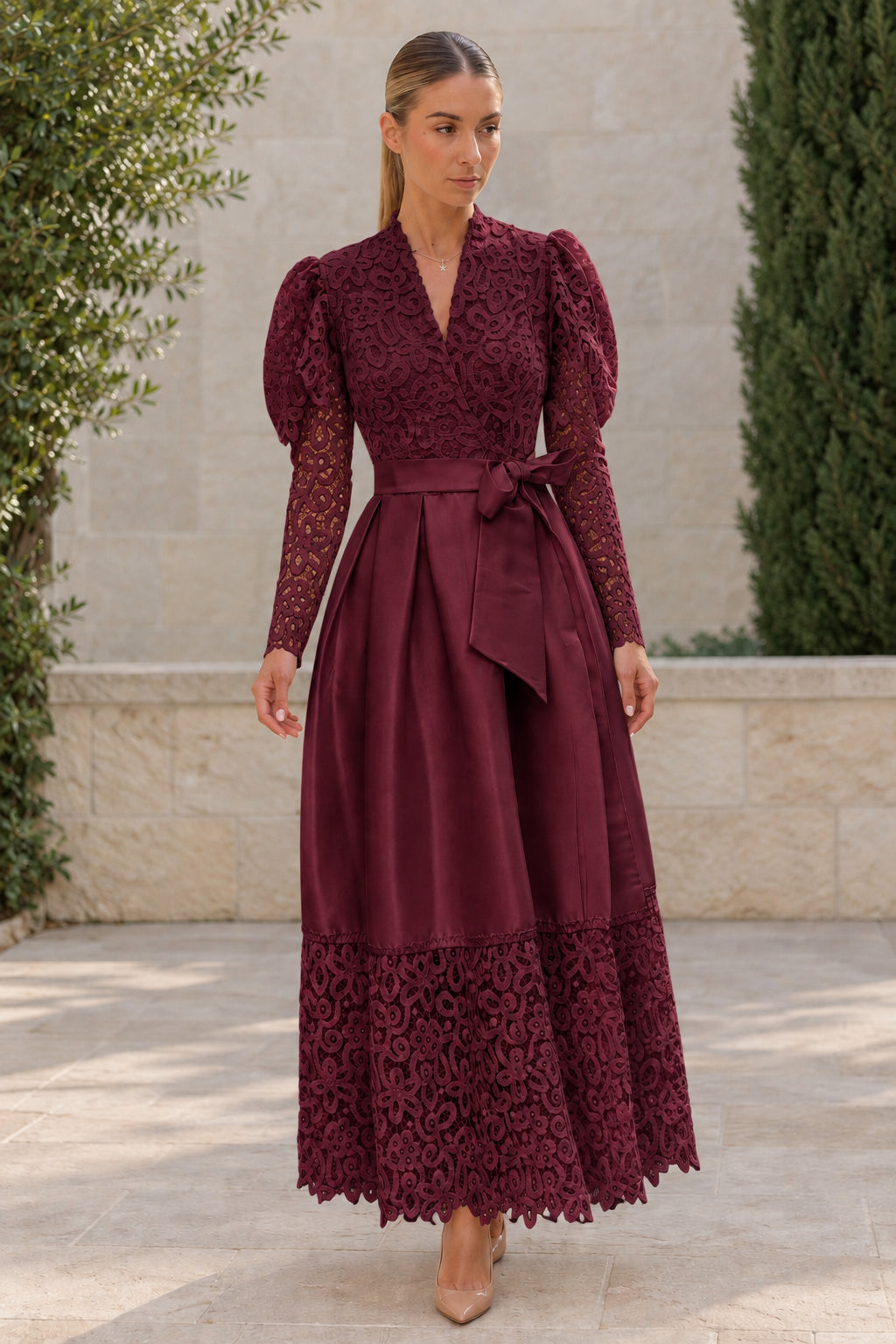 Woman wearing burgundy wine lace long sleeve pleated satin belted gown