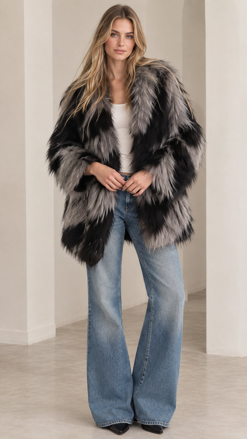 Front view of model wearing black and grey chevron shaggy faux fur coat with flare jeans