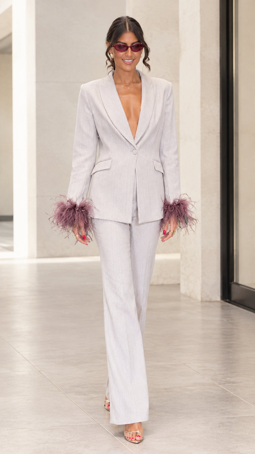 Front full-length view of woman wearing light grey tailored suit with mauve feather cuffs and flare pants