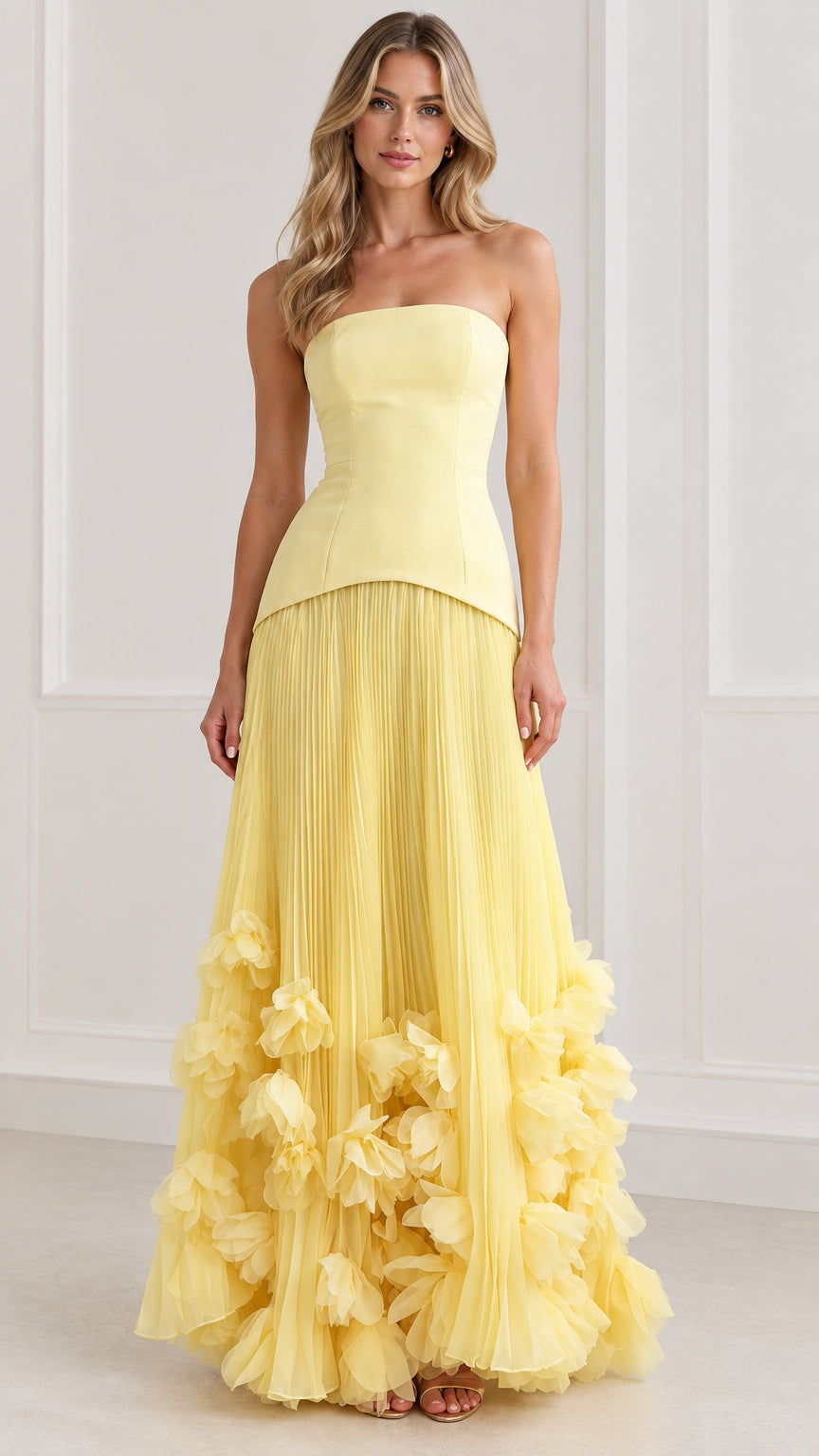 Front view of model wearing yellow strapless drop-waist corset maxi dress with 3D floral hem
