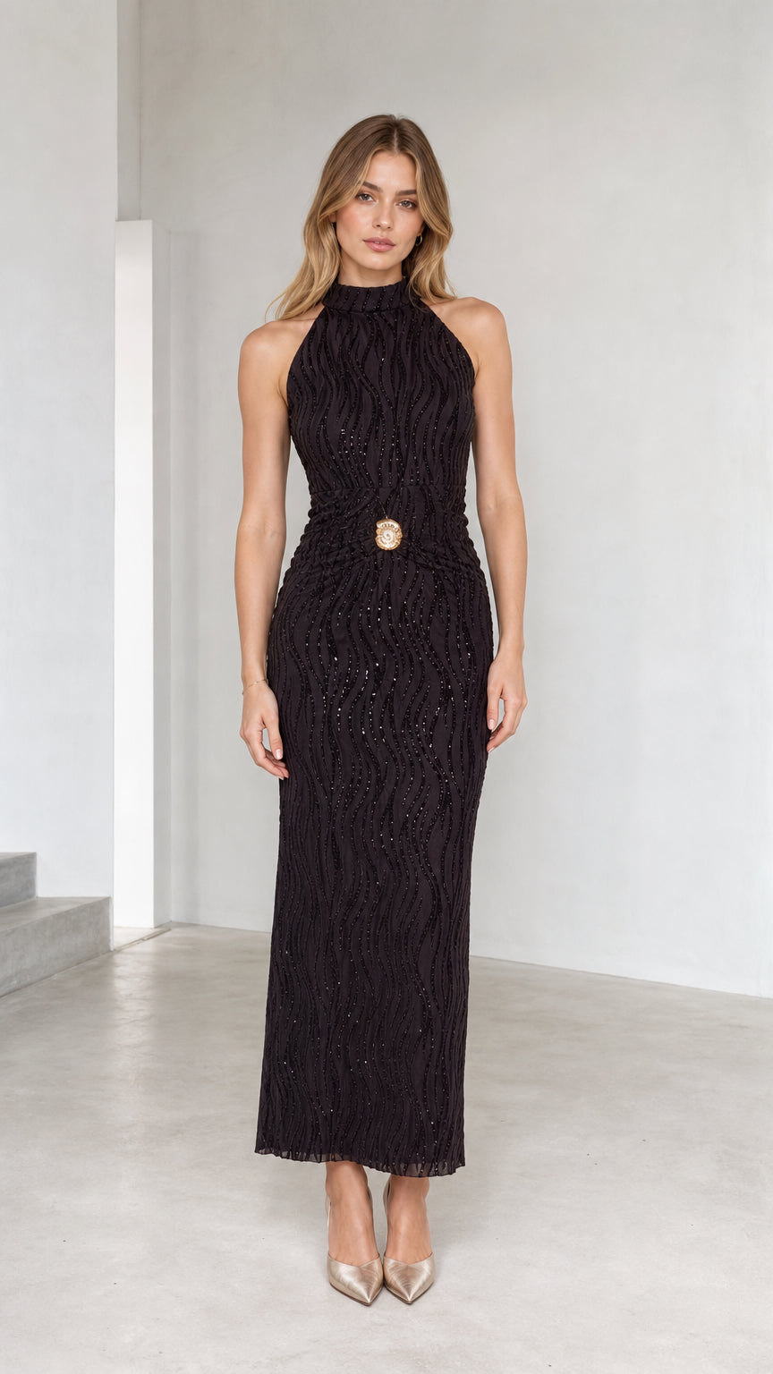 Model wearing black sleeveless high neck glitter maxi dress with gold waist medallion - front view