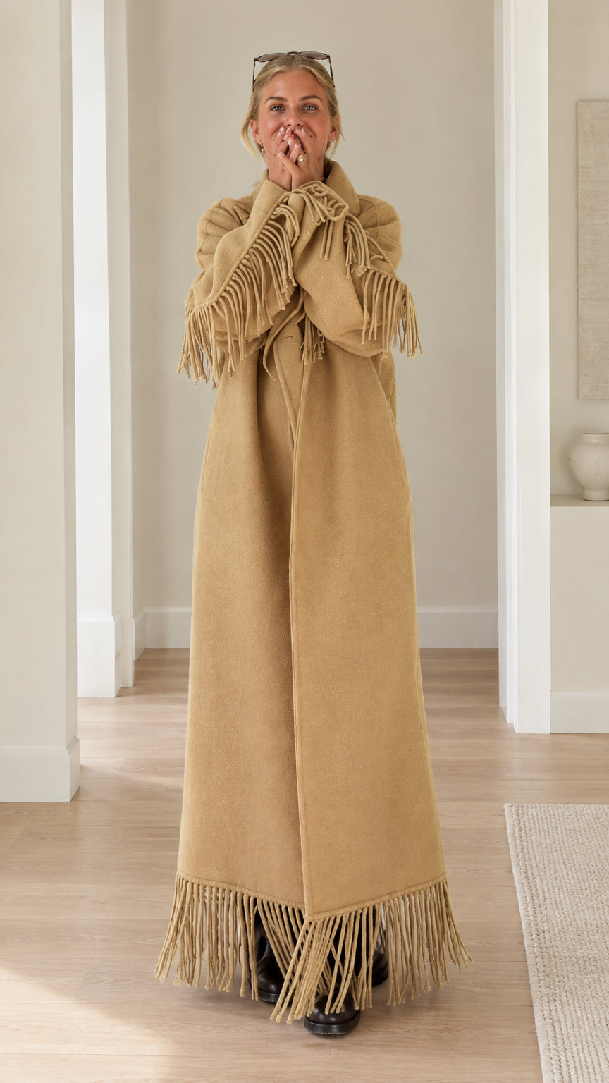 Front full-length view of woman wearing camel fringe trimmed maxi overcoat