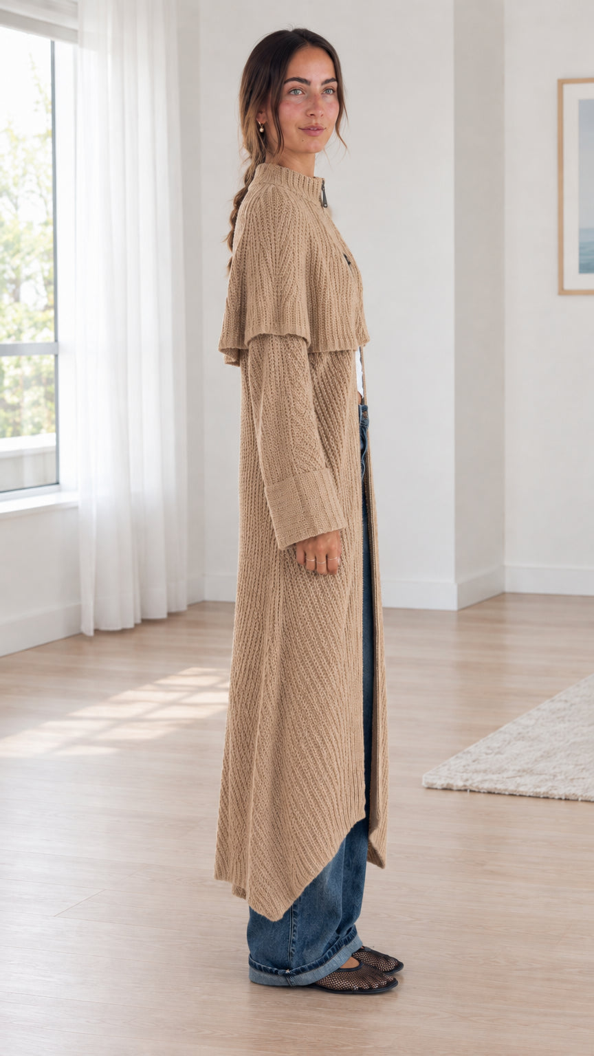Side profile of woman styling camel capelet knit duster coat with wide-leg jeans