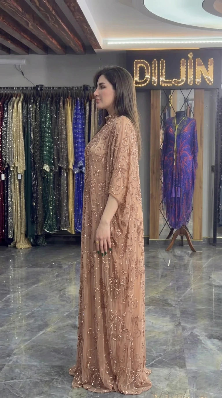 Side profile view of champagne beaded cape evening dress