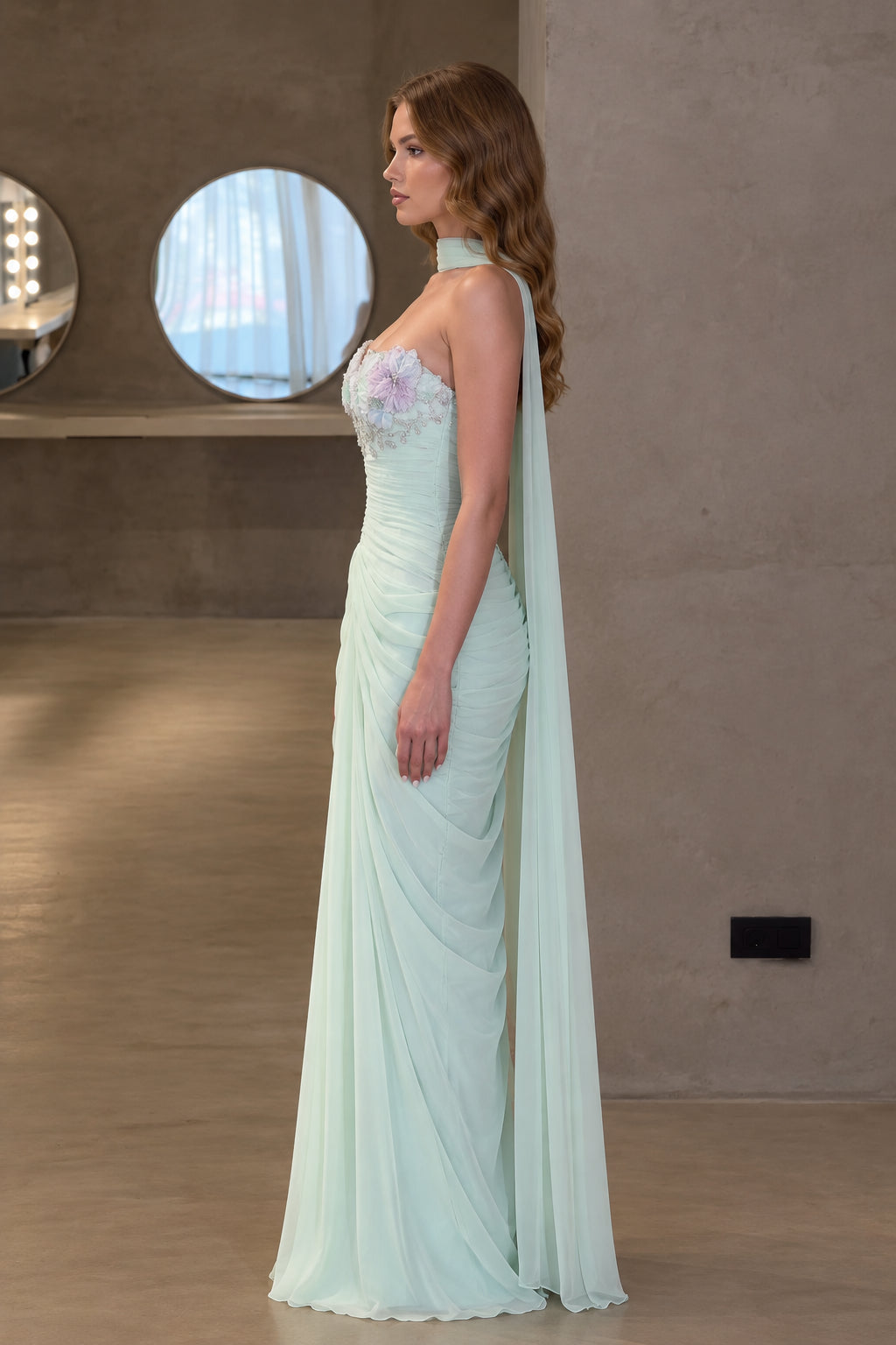 Side profile of mint green ruched maxi formal dress with draped cape scarf