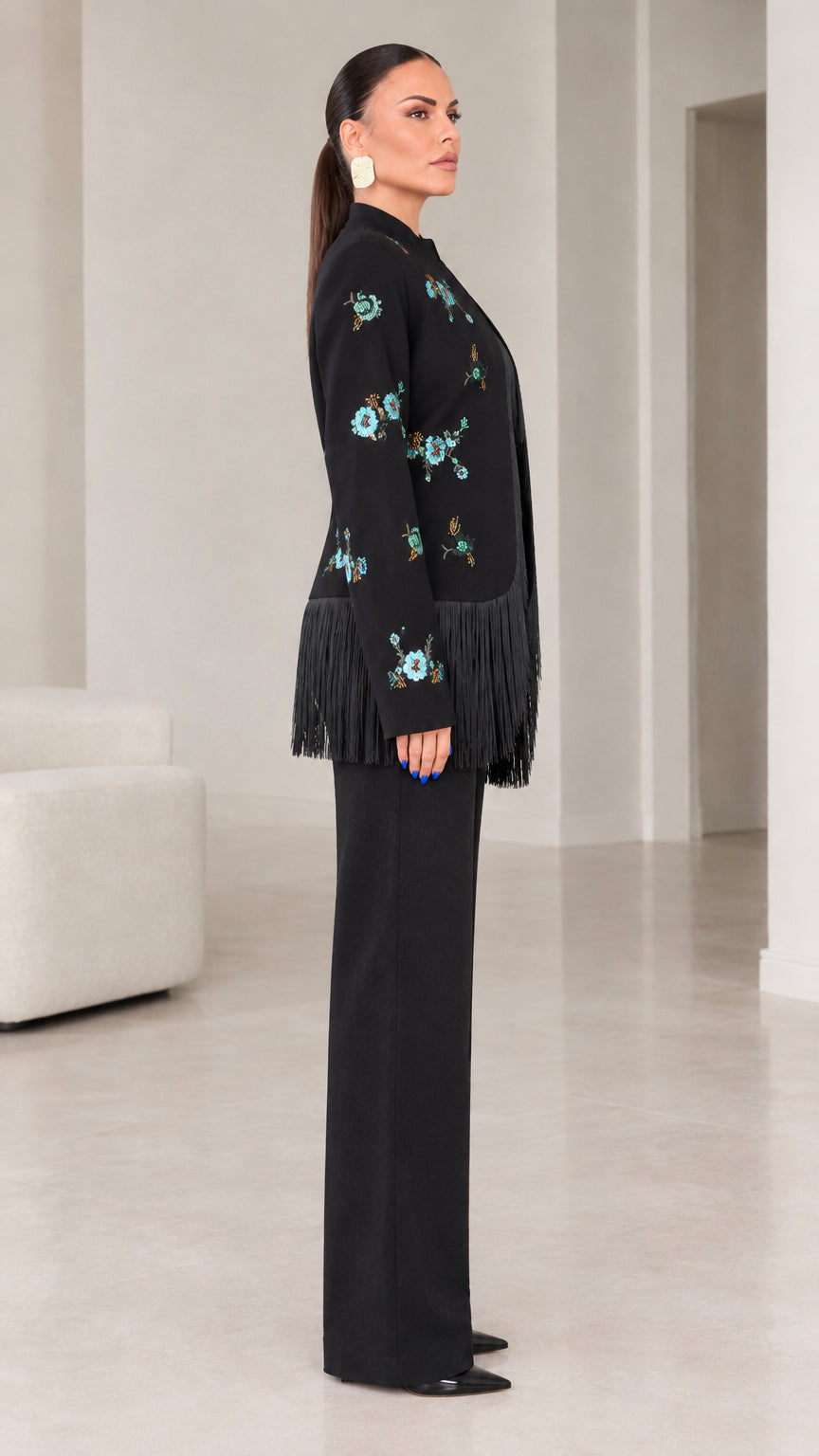 Side angle view of black embroidered blazer with fringe trim and tailored pants