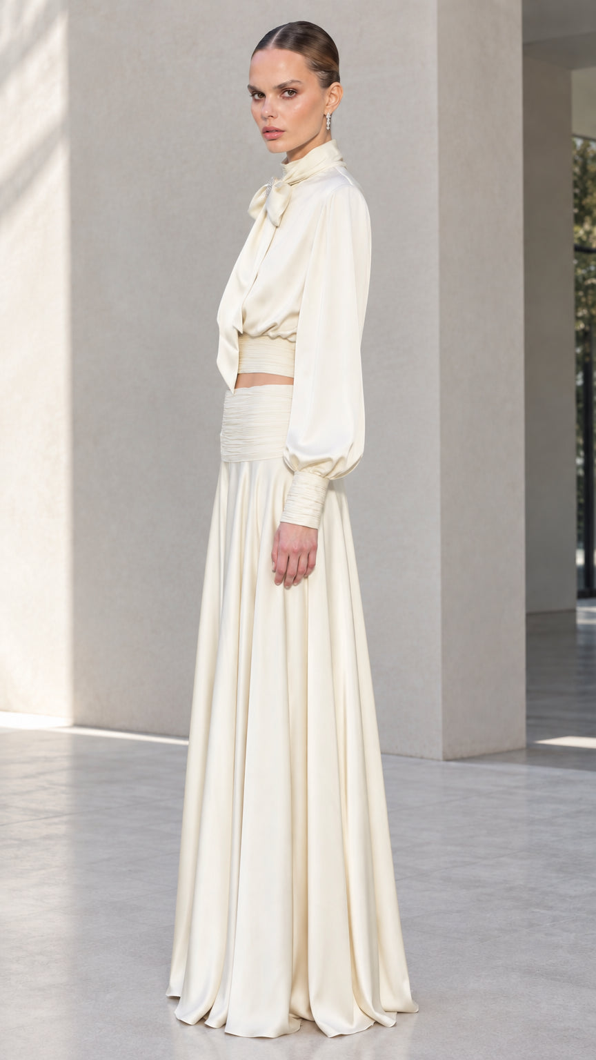 Side profile of model in ivory satin two-piece evening set with bishop sleeves
