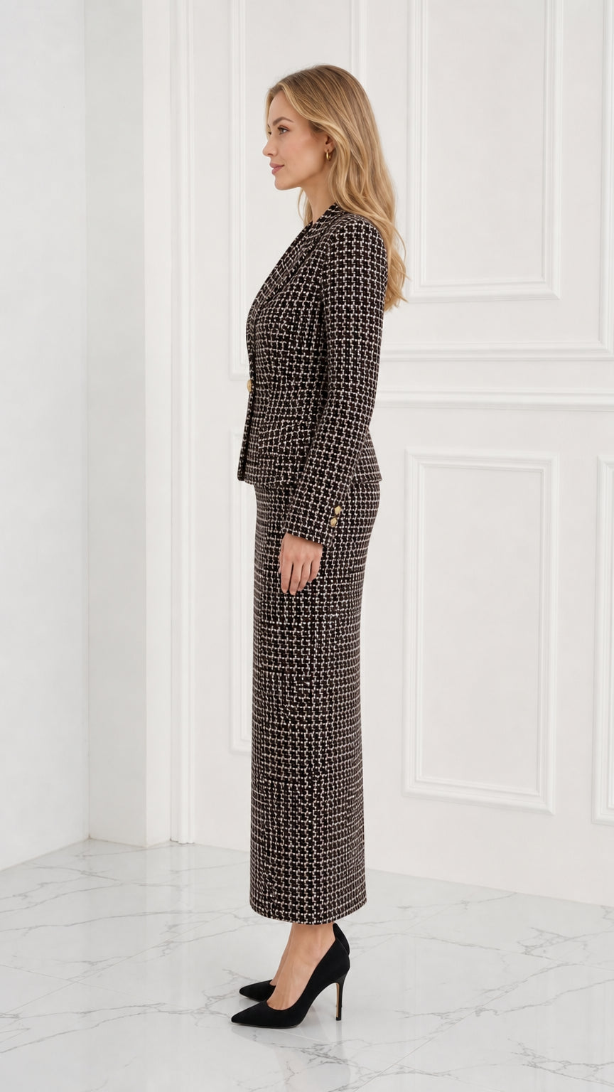 Side profile of model in tailored black tweed blazer and long column skirt
