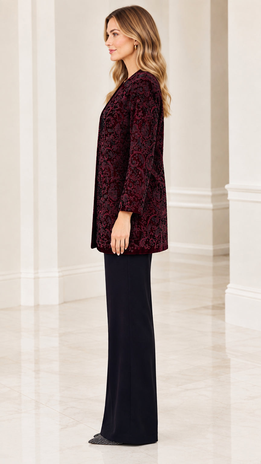 Side profile of woman in burgundy velvet evening duster jacket and black trousers