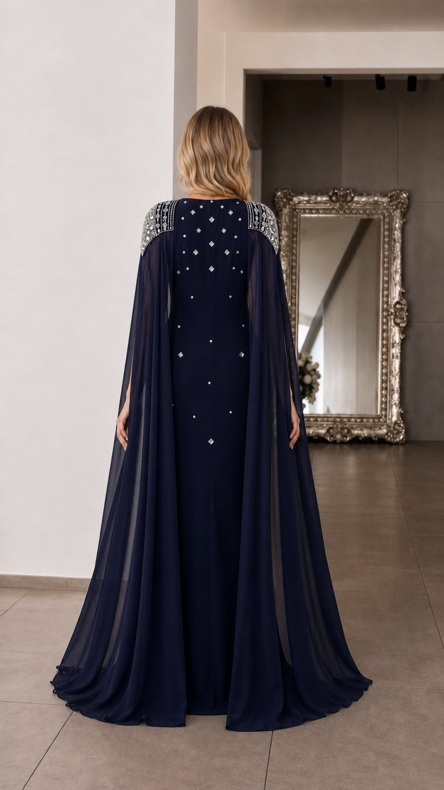 Back view of navy blue formal dress highlighting long sheer cape drape