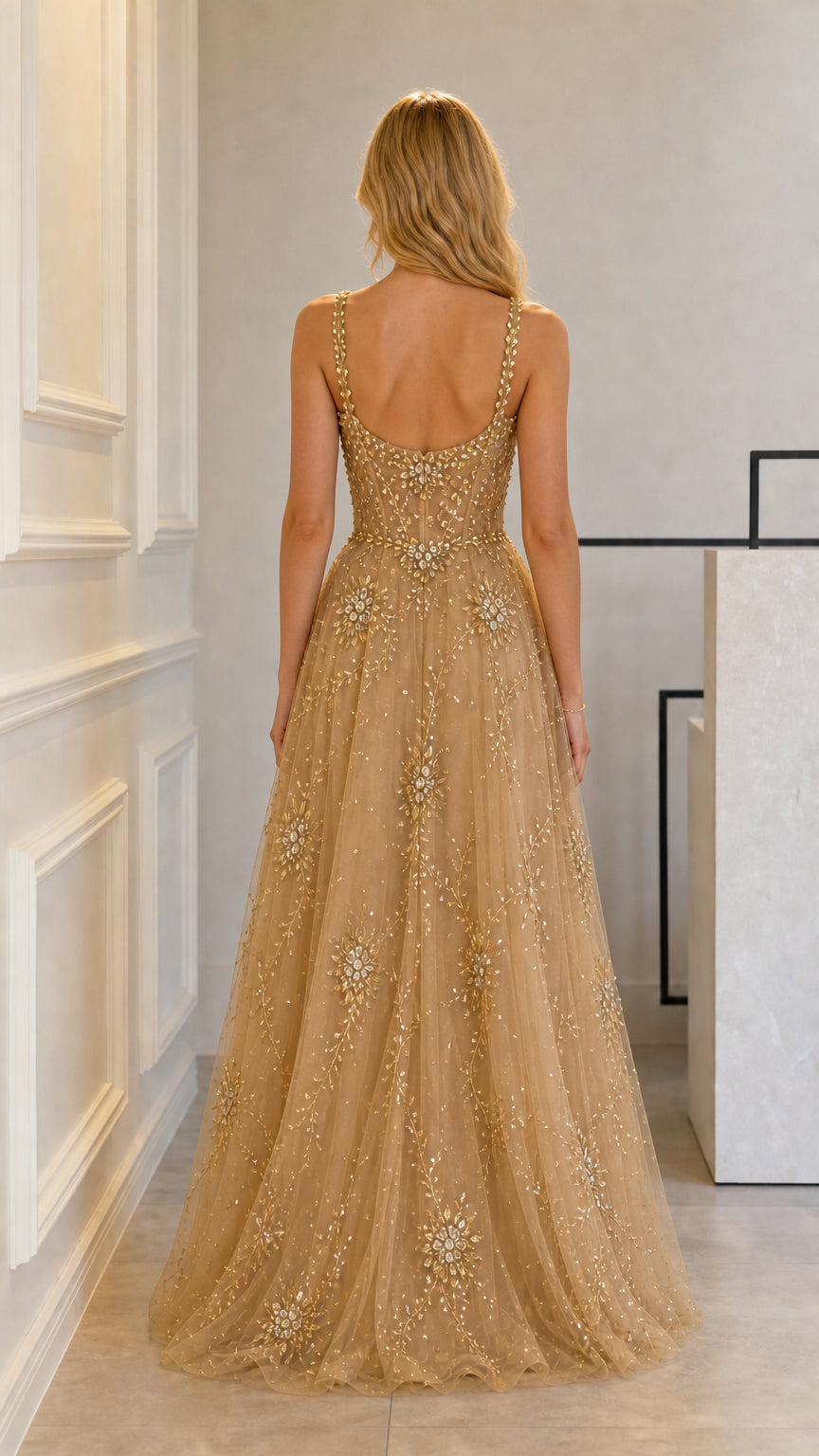 Back view of gold formal gown highlighting low scoop back and flowing tulle skirt