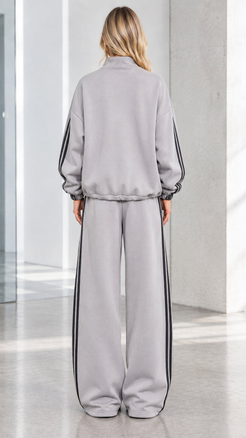 Back view of woman wearing Heather Grey relaxed track jacket and wide-leg pants