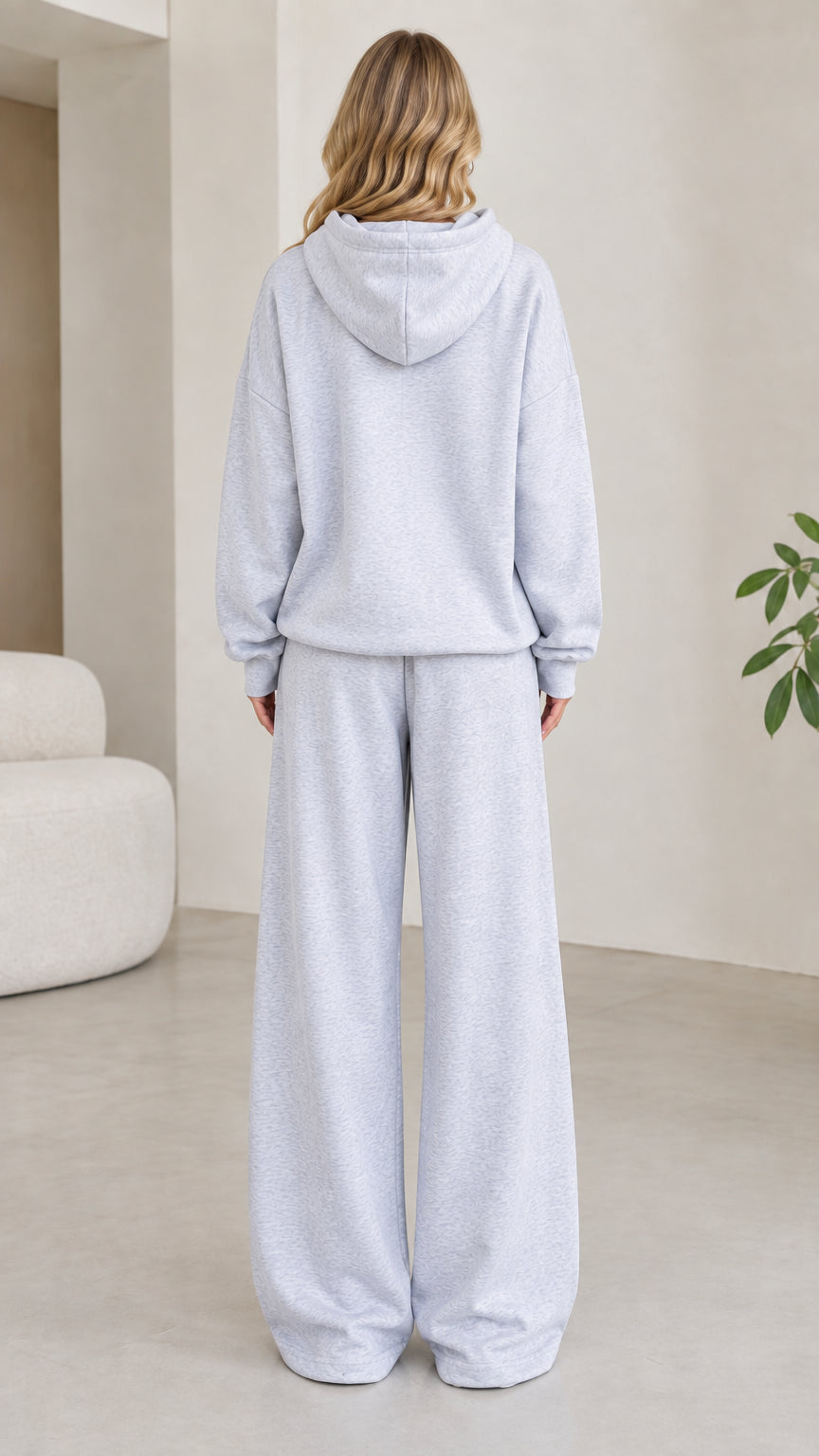 Back view of model wearing light grey hooded sweatshirt and matching wide leg pants