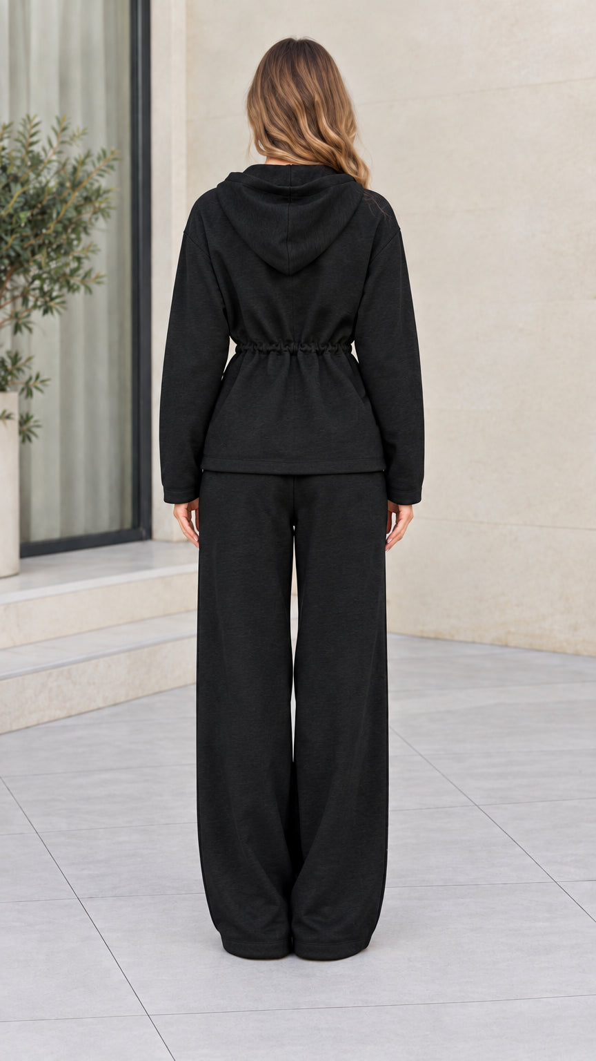 Back view of women wearing black hooded lounge jacket and wide leg pants set