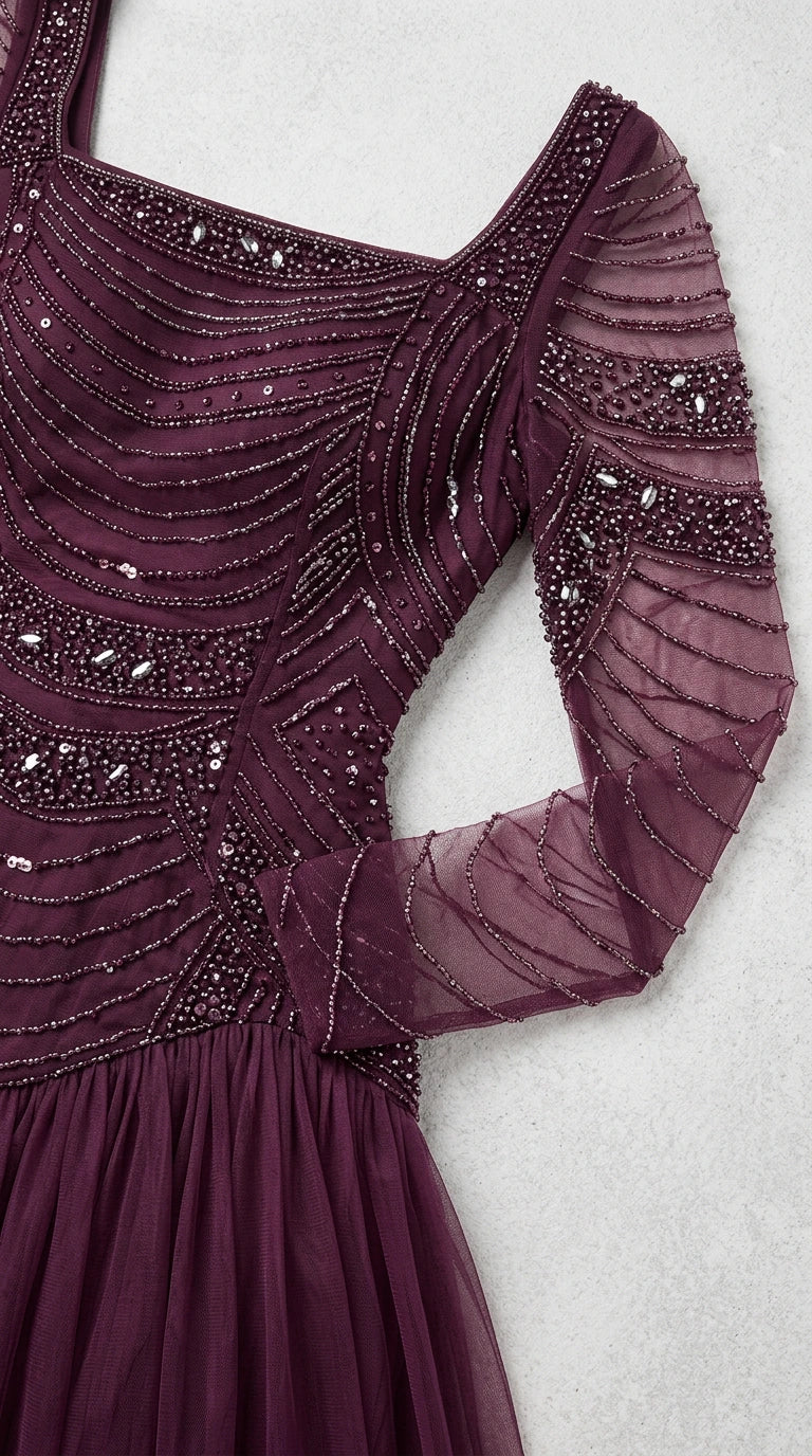 Close-up detail of intricate plum beadwork and sheer embellished sleeve on gown