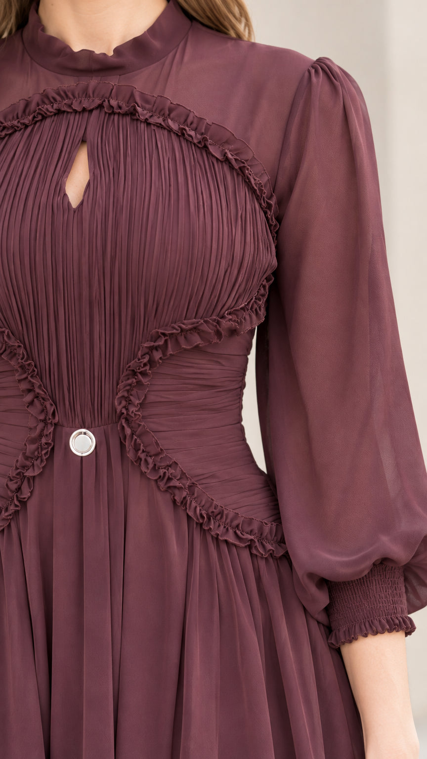 Close-up detail of burgundy bodice showing micro-pleating, keyhole cutout, and ruffle accents