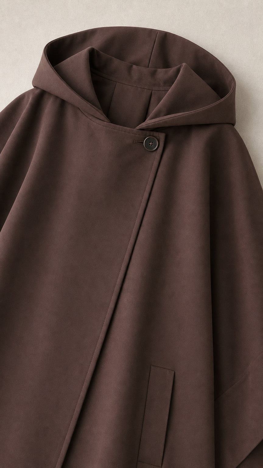 Close-up detail of brown cape hood and asymmetric button neckline