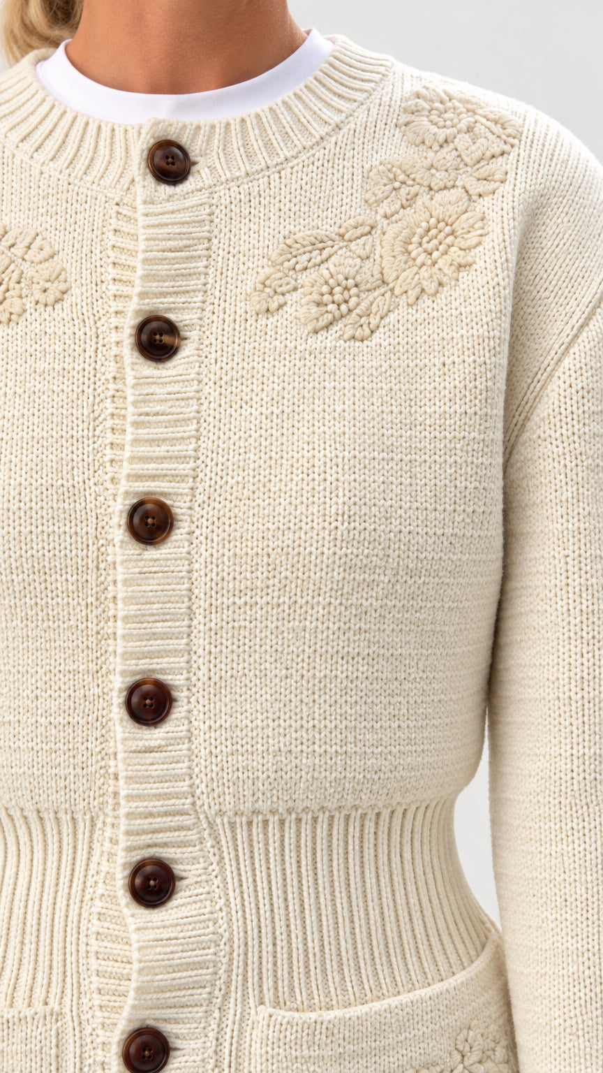 Close-up detail of textured floral embroidery and contrast buttons on Cream knit cardigan