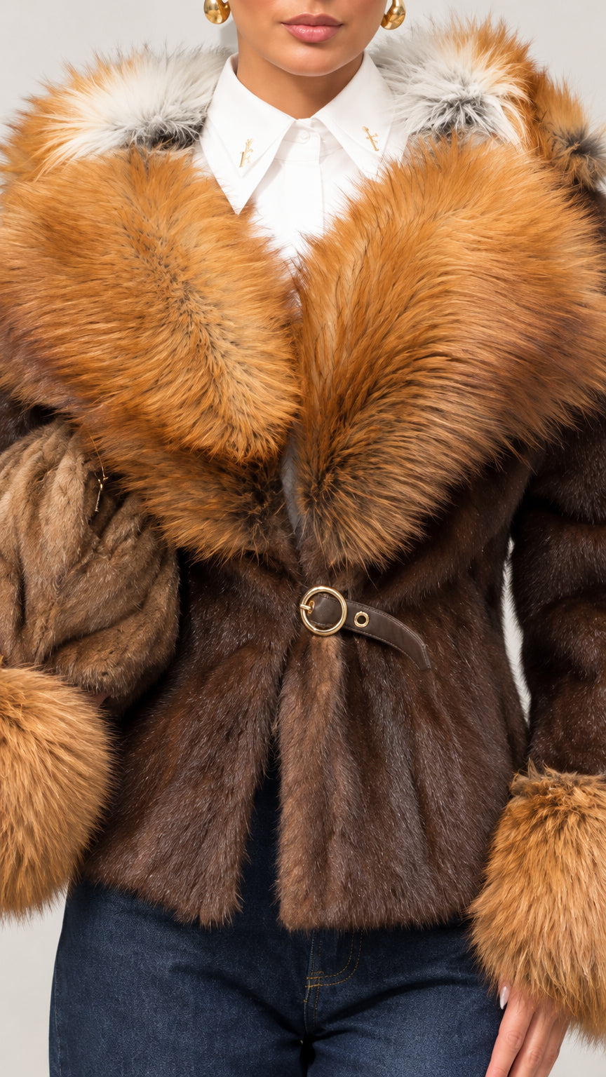 Close-up detail of brown jacket showing ring buckle closure, white collared shirt layer, and plush faux fur collar