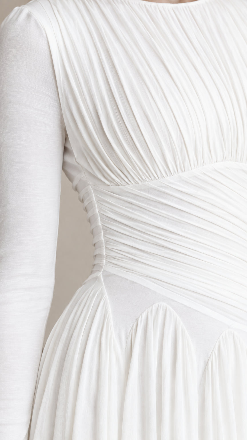 Close-up detail of textured pleating and waist construction on white dress