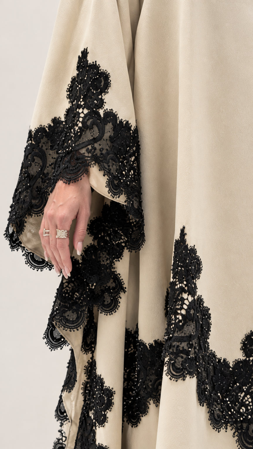 Close-up detail of intricate black floral lace trim on cream draped fabric
