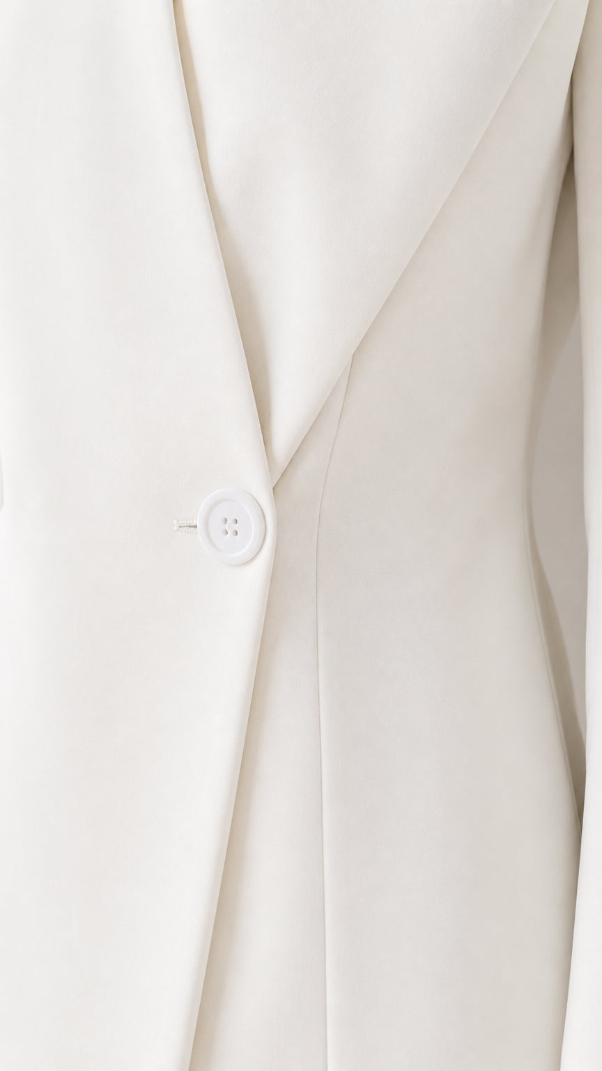 Close-up detail of white blazer lapel, tailored fabric texture, and single button closure