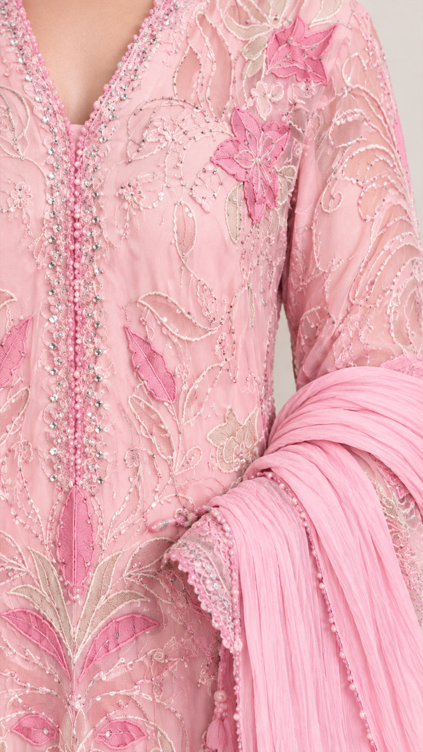 Close-up detail of bodice embroidery, beading, and textured scarf on light pink gown