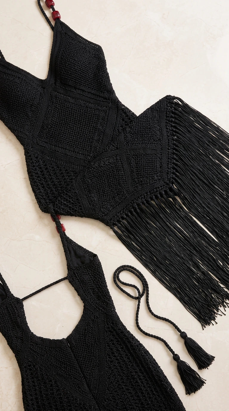 Close-up flat lay of black crochet knit pattern, beaded straps, and fringe trim