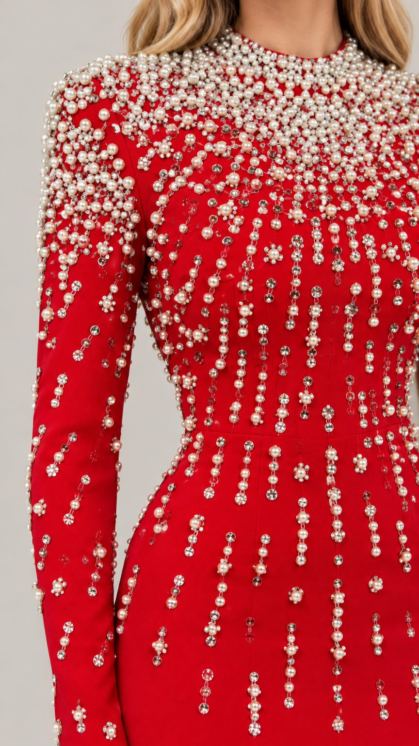 Close-up detail of cascading pearl and rhinestone embellishments on red fabric