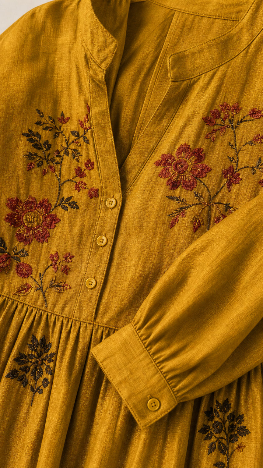 Close-up detail of floral embroidery and button placket on mustard dress