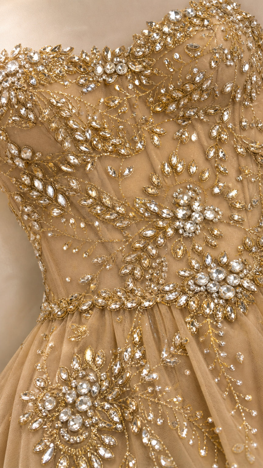 Close-up detail of gold gown showing intricate rhinestone floral embellishments on corset bodice