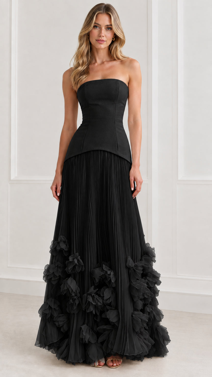 Front view of model wearing black strapless corset pleated maxi gown with 3D floral appliques