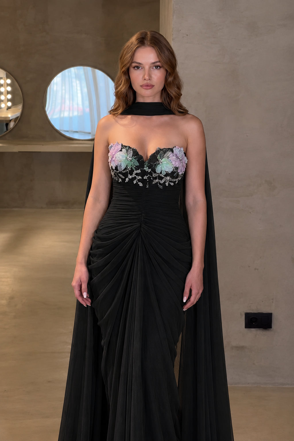 Front view of black ruched sweetheart evening gown with cape scarf