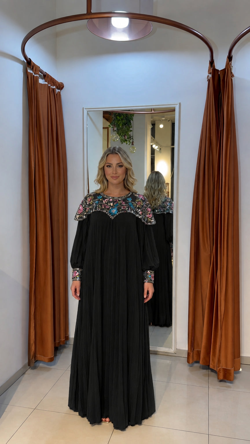 Woman wearing black pleated long-sleeve maxi dress with beaded yoke