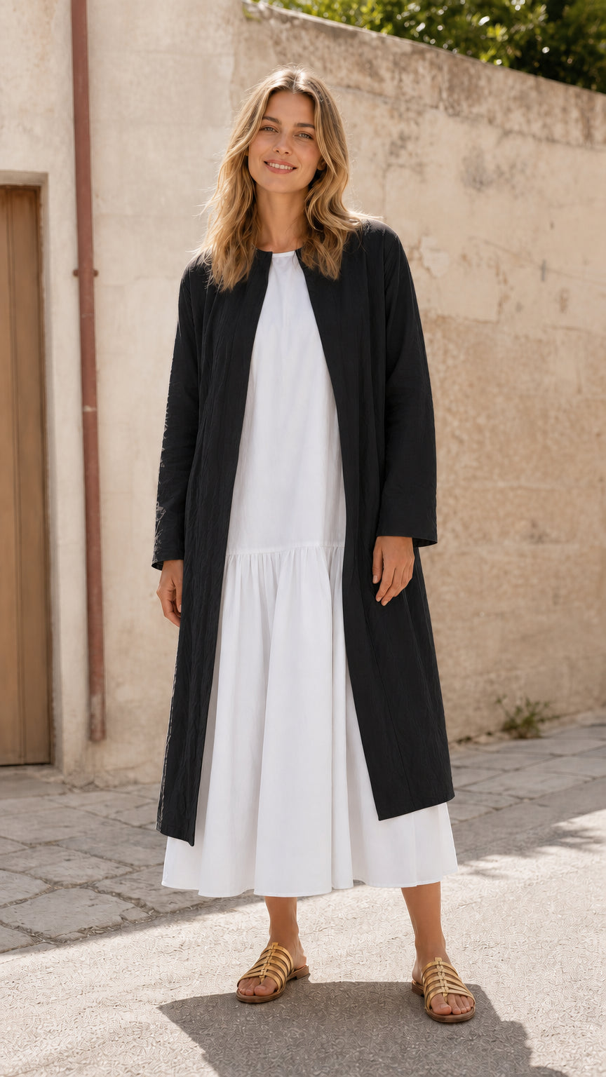 Woman wearing black open front longline duster coat over white dress