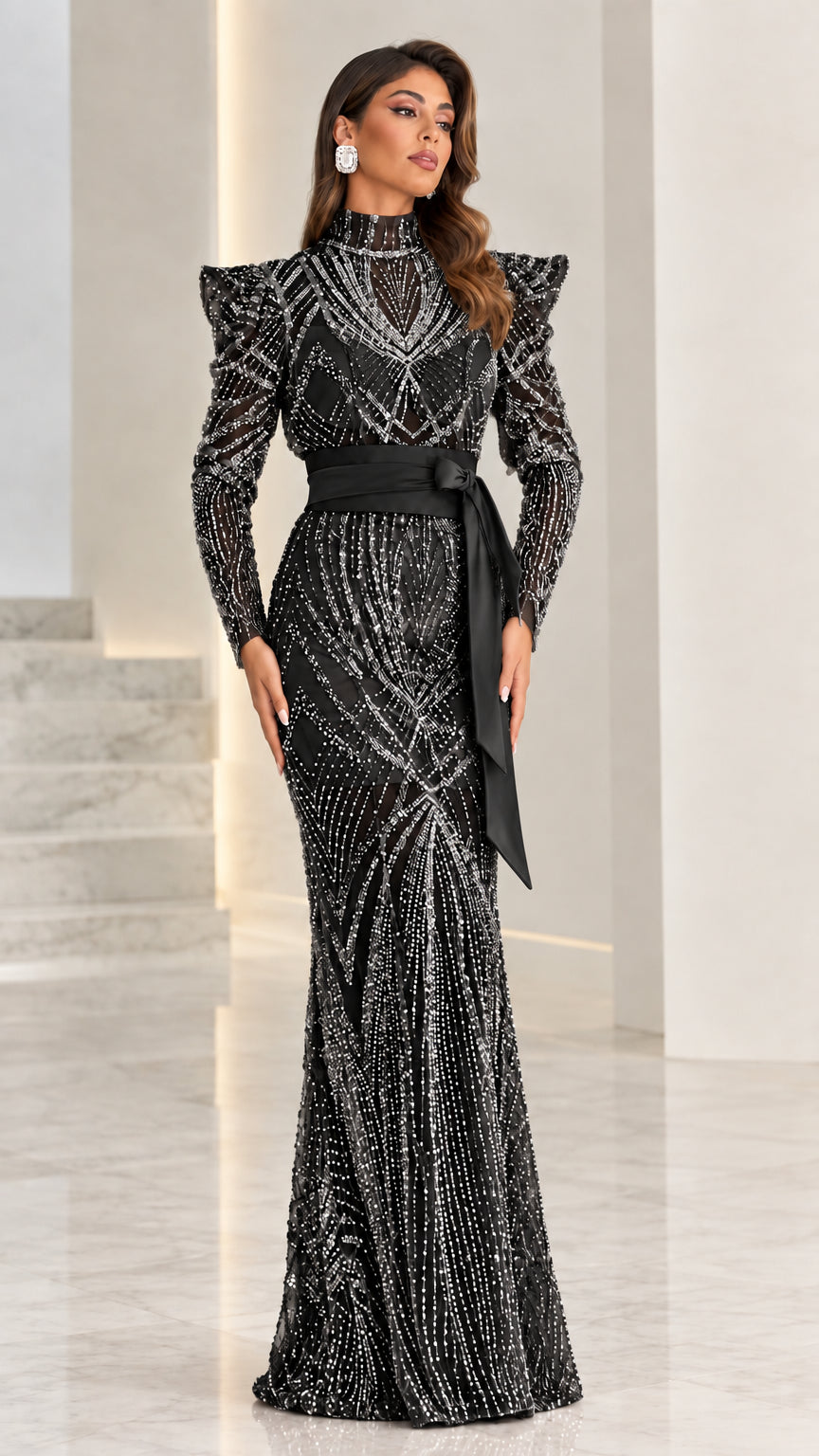 Model wearing black long-sleeve beaded formal gown with structured shoulders and sash