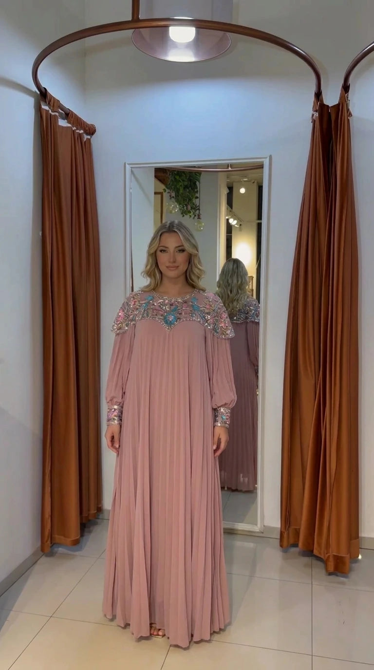 Woman wearing dusty pink pleated maxi gown with embellished neckline
