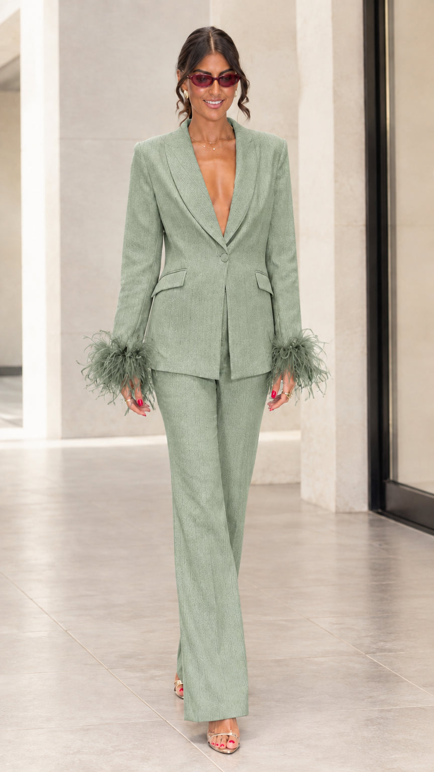 Front view of woman wearing sage green tailored suit set with green feather cuffs