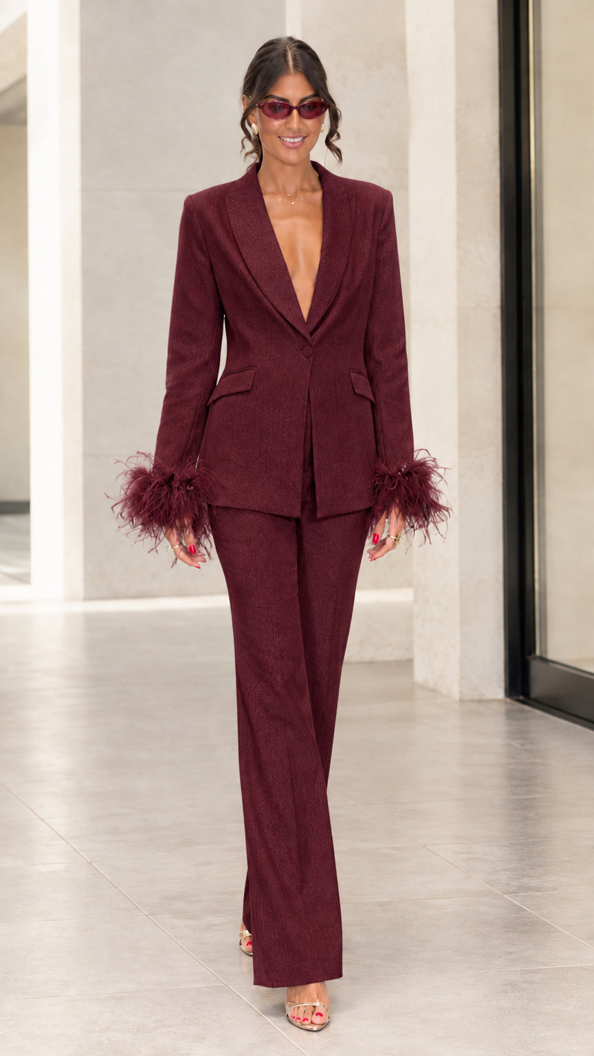 Front view of woman wearing burgundy tailored suit set with matching feather cuffs